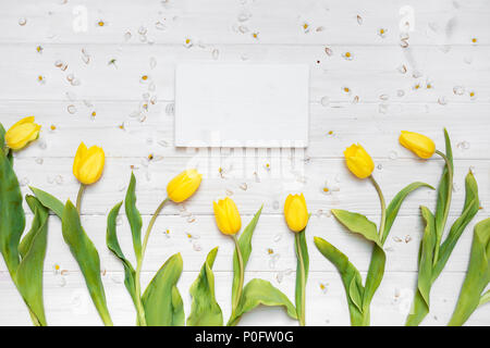 Scène de table blanc avec tulipes jaunes et cadre en bois blanc Banque D'Images