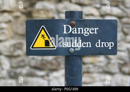 Danger brusque chute metal sign triangle jaune avec le symbole de l'homme tombe d'une falaise. Banque D'Images