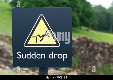 Danger brusque chute metal sign triangle jaune avec le symbole de l'homme tombe d'une falaise. Banque D'Images
