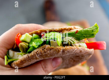 Main tenant vegetarian sandwich pita fourré aux asperges, poivrons, avocat et de feuilles fraîches. Banque D'Images
