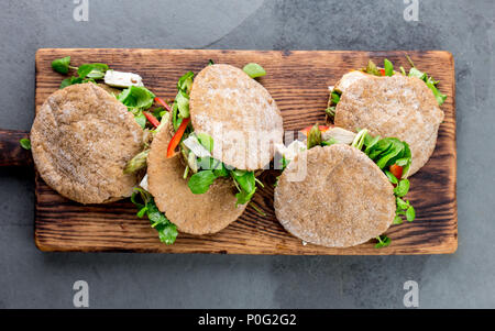 Des sandwichs pita farci au poulet, légumes et fromage sur planche à découper en bois. Banque D'Images