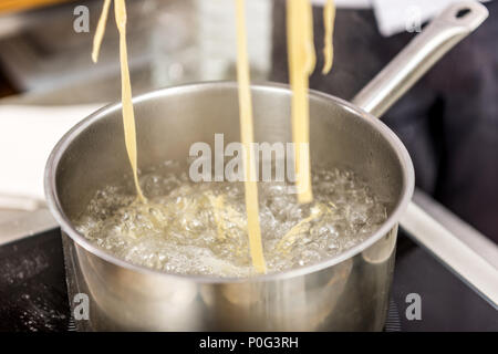 Les pâtes dans l'eau bouillante dans la casserole sur la cuisinière électrique Banque D'Images