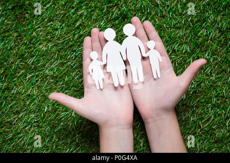 La main de l'holding paper cut de famille sur l'herbe Banque D'Images