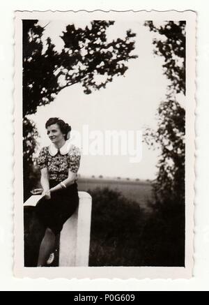 HODONIN, la République tchécoslovaque, vers 1930 : Vintage photo montre une jeune fille s'appuie contre point poste, vers 1930. Banque D'Images