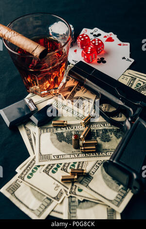 Concept de jeu avec gun, de whisky et de l'argent sur les jeux de table avec des cartes et des dés Banque D'Images