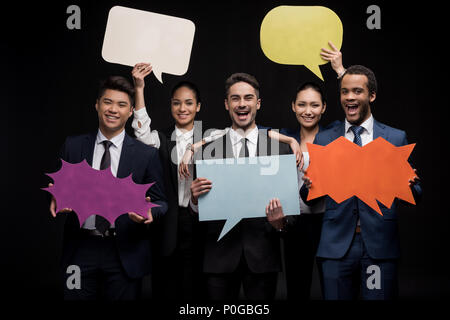 Group of businesspeople posing with blank Speech bubbles isolated on black Banque D'Images