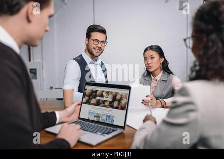 L'équipe entreprises multiethnique avec des documents et ordinateur portable avec le site depositphotos Banque D'Images