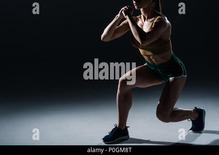 Portrait de femme bodybuilder sportive faisant mouvements brusques, sur noir Banque D'Images