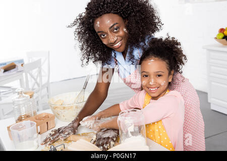 Smiling african american mother and daughter et pétrir la pâte de roulement et sur la cuisine Banque D'Images