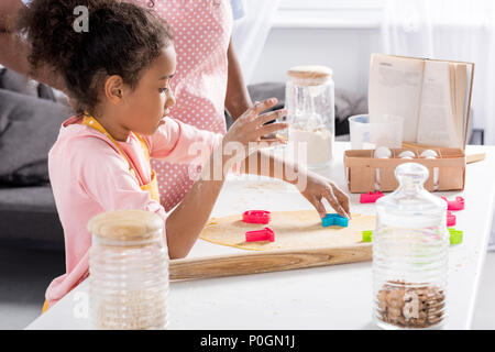 African American fille faire des biscuits avec un emporte-pièce sur la cuisine Banque D'Images