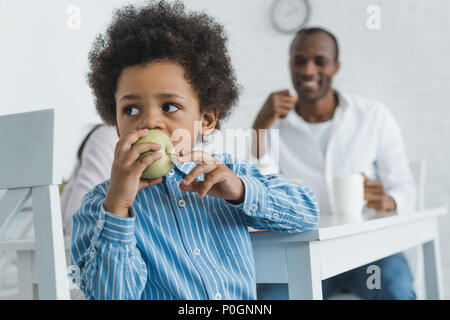 African American boy biting apple à la maison Banque D'Images