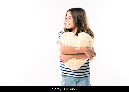 Smiling child hugging heart shaped pillow isolated on white Banque D'Images