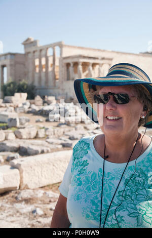 Senior woman in hat et lunettes de l'écoute d'une visite guidée dans les ruines d'Athènes Banque D'Images
