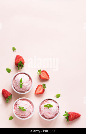 La crème glacée aux fraises et de fraises fraîches sur fond pastel rose, copiez l'espace. Trois boules de glace à la fraise, dessert d'été en bonne santé. Banque D'Images