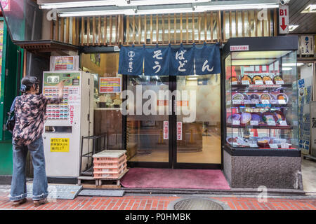 L'achat de billets de repas , femme de distributeur automatique, à l'extérieur restaurant de nouilles soba udon, Shinjuku, Tokyo, Japon Banque D'Images