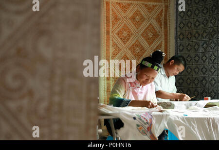 (180609) -- DANZHAI, le 9 juin 2018 (Xinhua) -- Une femme de l'ethnie miao batik, attire avec son mari à Yangwu Ville de Danzhai County, au sud-ouest de la province du Guizhou, en Chine, le 8 juin 2018. Le peuple Miao artisanat batik est l'un des patrimoines immatériels nationaux de la Chine. Comme le principal site de l'héritage du peuple Miao Miao artisanat batik, la Jijia Village de Yangwu ville a un bon nombre d'excellents artisans, mais le trafic gênant avaient empêché la vente de produits de batik vers l'extérieur avant 2017. Avec l'augmentation de l'amélioration de la circulation et l'aide du gouvernement local et volu Banque D'Images