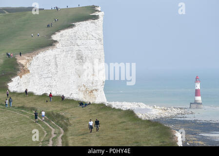 South Downs, au Royaume-Uni. 9 juin 2018. Des excursions à pied le long de la South Downs Way près de l'Beachy Head Lighthouse sur une chaude après-midi. Au cours des dernières années, la région a été sujettes à l'érosion, avec des zones de falaises de craie autour de la fusion de sept soeurs sur la plage ci-dessous. En conséquence les marcheurs sont mis en garde de ne pas aller près du bord de la falaise. Crédit : Stephen Chung / Alamy Live News Banque D'Images