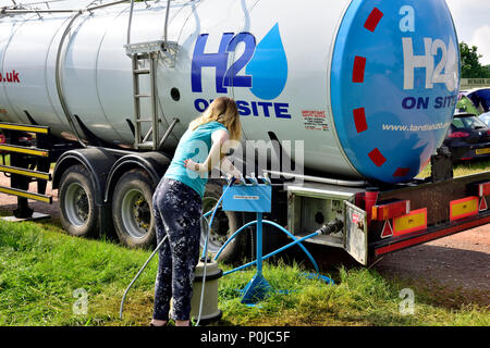 Dame obtenir de l'eau potable à partir de l'approvisionnement pétrolier pour le camping au festival Banque D'Images