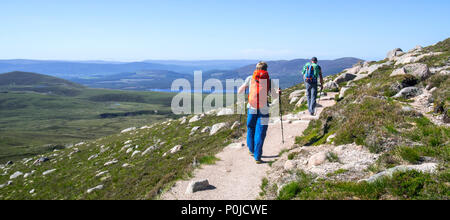 Deux alpinistes / les randonneurs avec bâtons de randonnée et des sacs à dos en ordre décroissant sentier de montagne au printemps dans le Parc National de Cairngorms, Highland, Scotland Banque D'Images