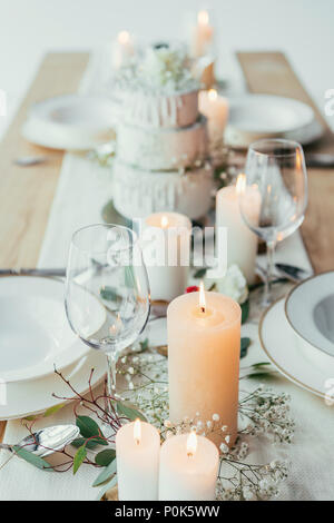 Vue rapprochée de l'établissement table élégante avec des bougies, et les plateaux vides wineglasses pour mariage rustique Banque D'Images