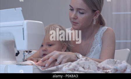 Petit enfant apprend de nouvelles connaissances avec sa mère à l'aide de la machine à coudre Banque D'Images