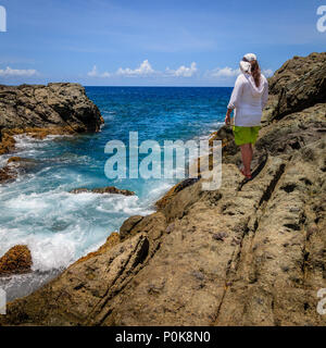 Une femme debout sur une falaise et regarder surfer sur une île de BVI Banque D'Images