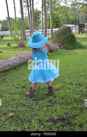 Petite fille en robe bleue dans une ferme. Banque D'Images