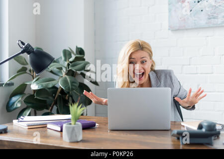 Surpris businesswoman looking at laptop in office Banque D'Images