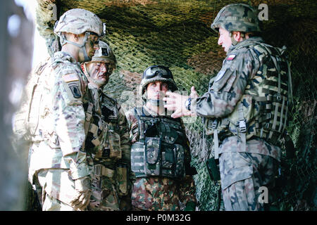 (De droite à gauche) Polish Brig. Le général Jarosław Gromadziński, le Major roumain Octavian Musat, R.-U. Le Major Ben Parkyn et le lieutenant-colonel de l'armée américaine Adam Lackey, commandant du Groupement tactique de la Pologne, de discuter de l'exploitation au cours de la cérémonie d'ouverture de grève 18 Sabre avec Battle Group Pologne à Wierzbiny, Pologne, le 4 juin 2018. Grève de sabre est un exercice multinational en ce moment à sa huitième année. L'exercice de cette année, qui se déroulera du 3 au 15 juin, des tests des alliés et des partenaires de 19 pays sur la capacité de travailler ensemble pour prévenir les agressions dans la région et d'améliorer la capacité de chaque unité d'exercer l'effet Mlle Banque D'Images