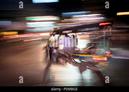 Résumé technique de panoramique de la création d'un flou de mouvement et un tuktuk véhicule conduire la nuit dans les rues de Chiang Mai dans le nord de la Thaïlande Banque D'Images