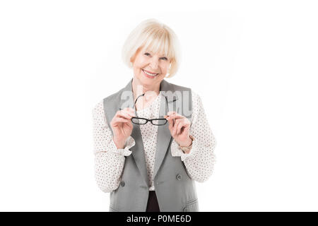 Smiling senior businesswoman holding eyeglasses élégant isolated on white Banque D'Images