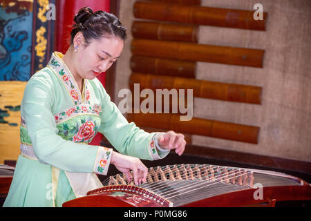 Yangzhou, Jiangsu, Chine. Jeune femme jouant du guzheng, mince West Lake Park. Banque D'Images