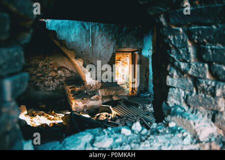 Vue depuis une fenêtre d'une maison abandonnée avec une porte à l'écran rétroéclairé par le soleil Banque D'Images