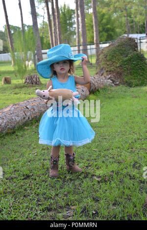 Petite fille en robe bleue dans une ferme. Banque D'Images