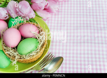 Concert de Pâques : bouquet de tulipes roses fleurs et oeufs de Pâques, de la plaque et de la coutellerie sur nappe à carreaux, avec copie-space Banque D'Images