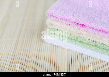 Pile de serviettes éponge propre multicolores sur un tapis de bambou, avec un espace réservé au texte Banque D'Images