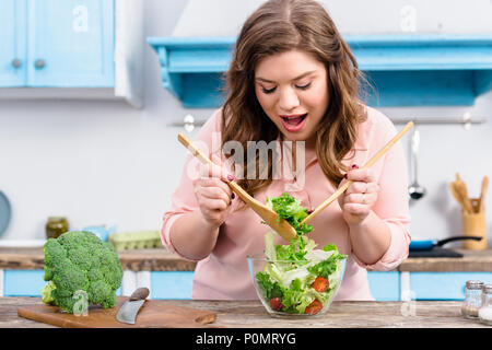 Portrait de l'excès de cuisson femme émotionnelle salade fraîche pour le dîner dans la cuisine à la maison Banque D'Images