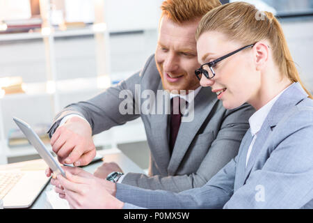 Businessman et businesswoman having conversation et using digital tablet in modern office Banque D'Images