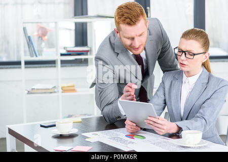 Businessman et businesswoman having conversation et using digital tablet in modern office Banque D'Images