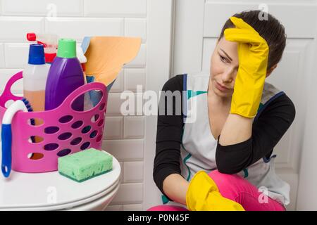 Tired woman sitting on salle de bains marbre avec des produits de nettoyage et d'équipement. Banque D'Images