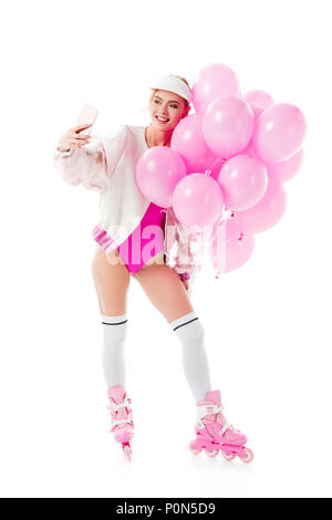 Jeune fille portant des vêtements roses et de patins holding balloons en tenant isolé sur blanc selfies Banque D'Images