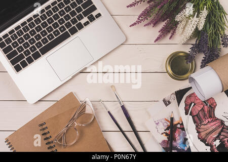 Vue de dessus de l'ordinateur portable, fleurs, plan directeur, les ordinateurs portables avec les lunettes et les croquis de mode sur table en bois haut Banque D'Images