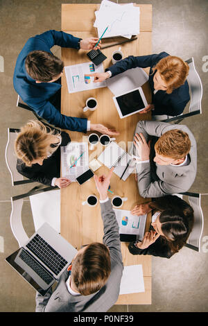 Vue de dessus d'affaires sur réunion au tableau avec les appareils numériques, des tasses à café et des documents Banque D'Images