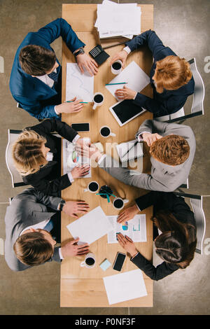 Vue de dessus du couple à table avec les appareils numériques, des tasses à café et des documents Banque D'Images