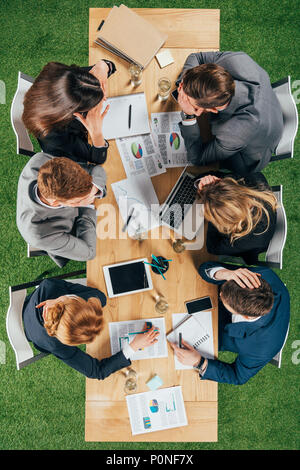 Vue de dessus de partenaires d'affaires ayant discussion à table avec les appareils et documents in office Banque D'Images