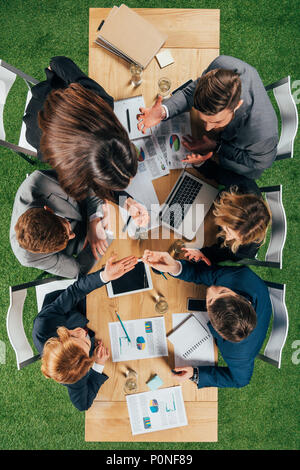 Vue de dessus de la colère des partenaires commerciaux ayant la discussion à table avec les documents et appareils à l'office de tourisme Banque D'Images