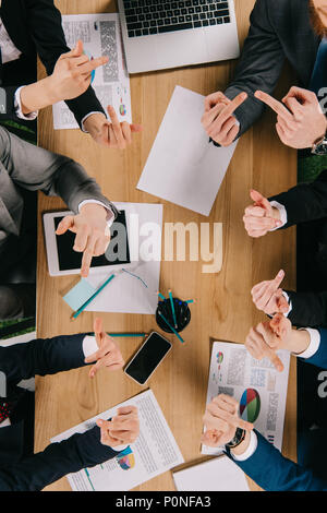 Portrait of businesspeople montrant doigts du milieu à l'autre à table Banque D'Images