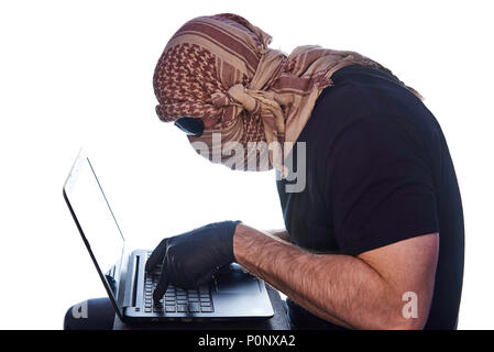 L'homme caché sous les verres noirs et arafatka garde ses mains dans des gants noirs sur l'ordinateur portable. Banque D'Images