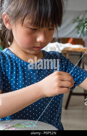 Suzhou, Jiangsu, Chine. Petite fille pratiquant la broderie. Banque D'Images