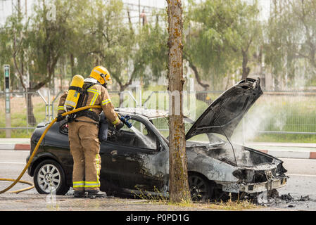 Les pompiers éteindre une voiture qui a brûlé dans une rue de Barcelone. Banque D'Images